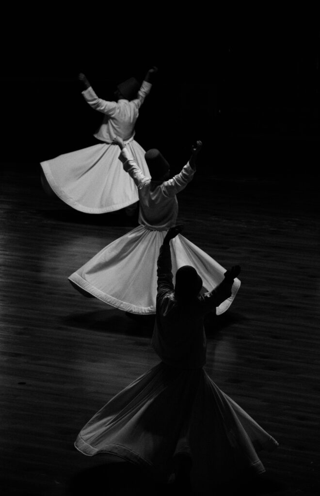 Black and white photo of Sufi whirling dervishes in Konya, embodying spirituality and tradition.